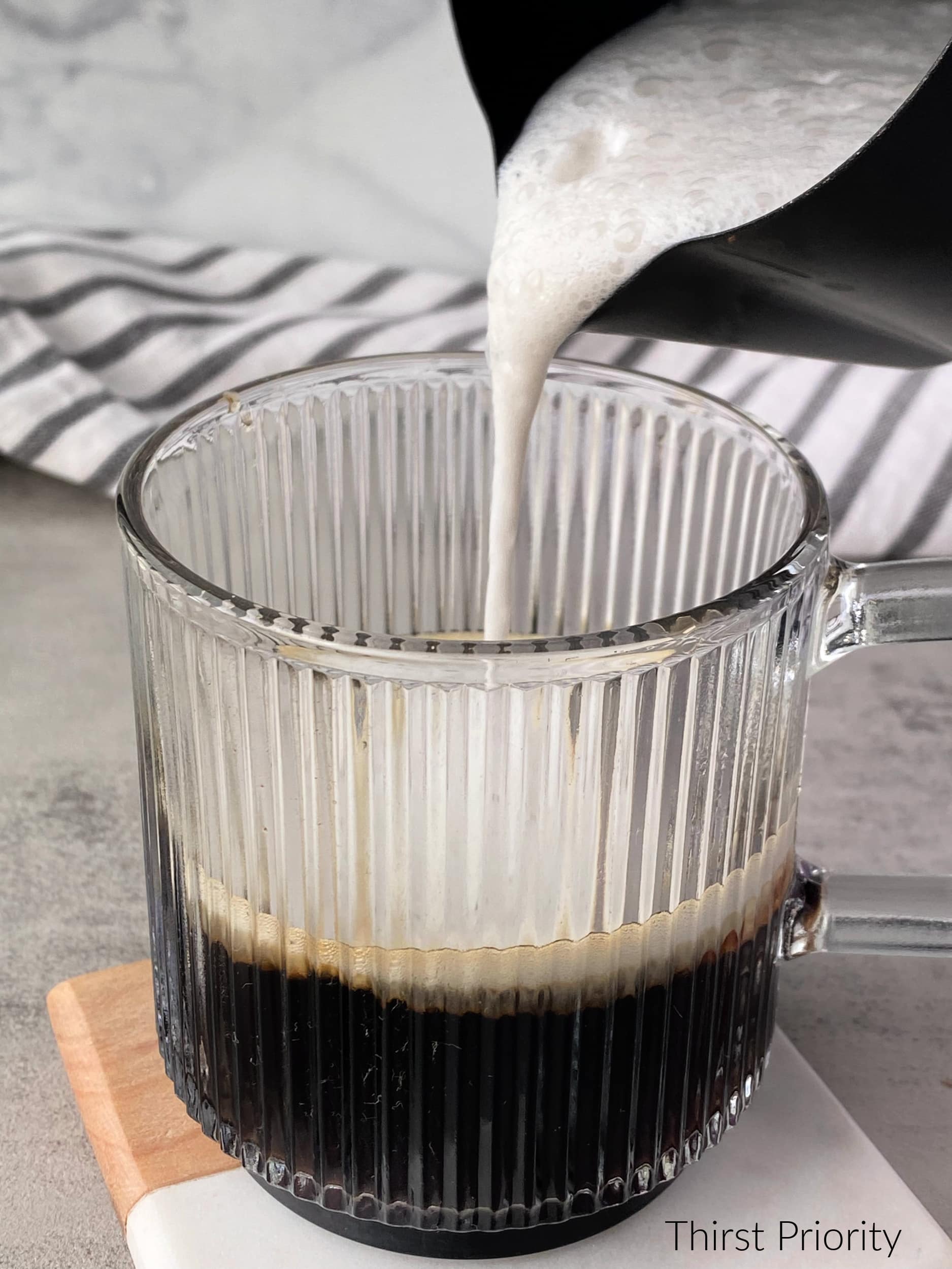 pour frothed milk into coffee mug